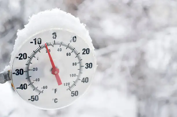 A thermometer showing freezing temperatures and falling snow in Yellowknife, Northwest Territories.  Blurred snow background for good copy space image right.  Close up.