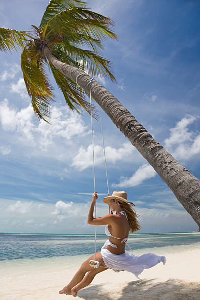 istock woman swinging at a tropical beach 157512042
