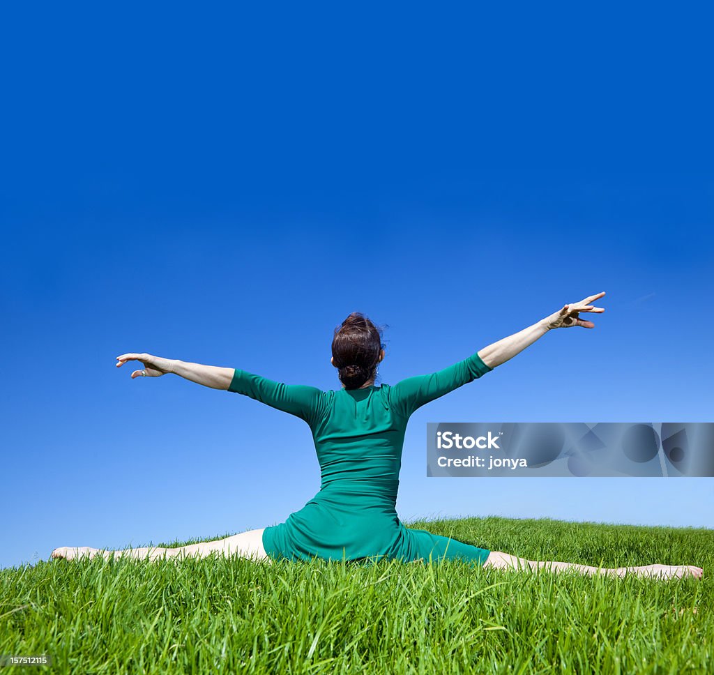 dancer doing splits on green grass with arms extended  Activity Stock Photo
