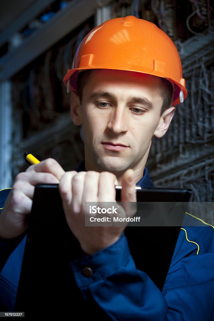 Construction engineer in automatic switching center taking notes Maintenance-communicative engineer taking notes on the job &#1089;&#1074;&#1103;&#1079;&#1085;&#1086;&#1081; Activity Stock Photo