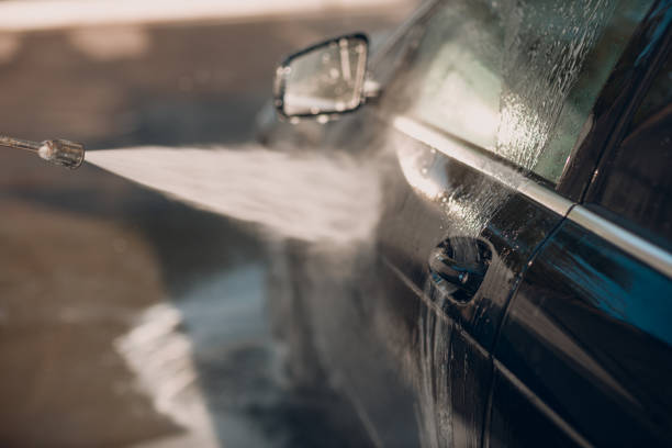 istock Worker washing car at self-service car wash 1575124411
