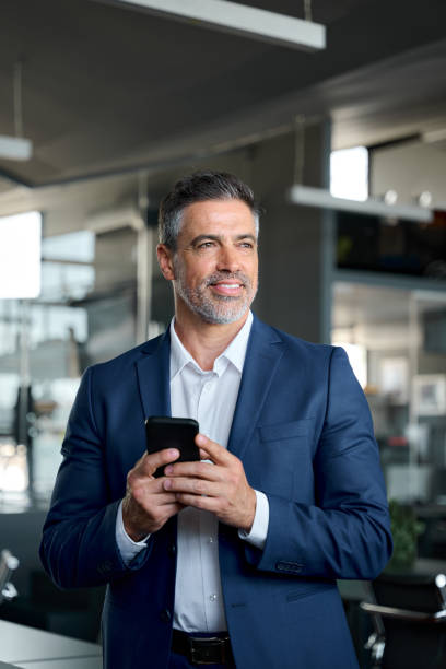 istock Confident mature businessman leader wearing suit using phone in office. 1575126010
