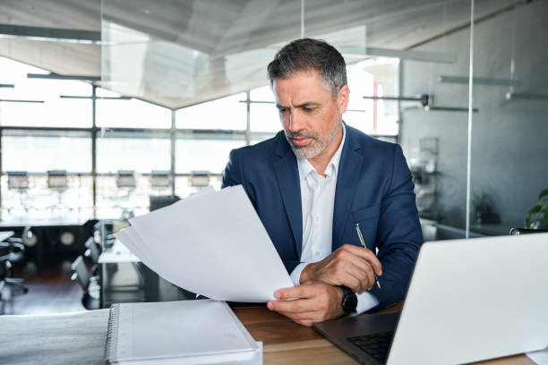Serious mid aged business man ceo checking corporate financial document.