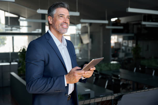 istock Happy middle aged business man wearing suit in office using digital tablet. 1575126046