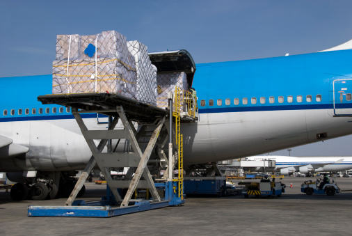 High loader with cargo pallet putting the cargo into a Boeing 747 airplane maindeck cargo compartment. The cargo door of this blue Boeing  747 combi aircraft is open.