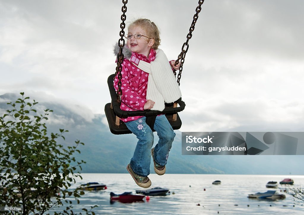 Bambina su altalena A waterfront - Foto stock royalty-free di Bambino