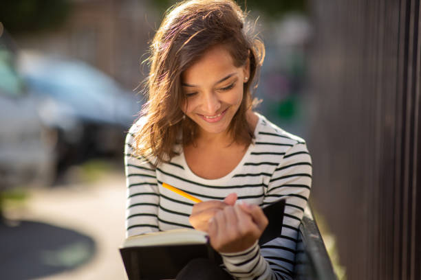 istock Close up beautiful young woman smiling and writing in diary 1575128857