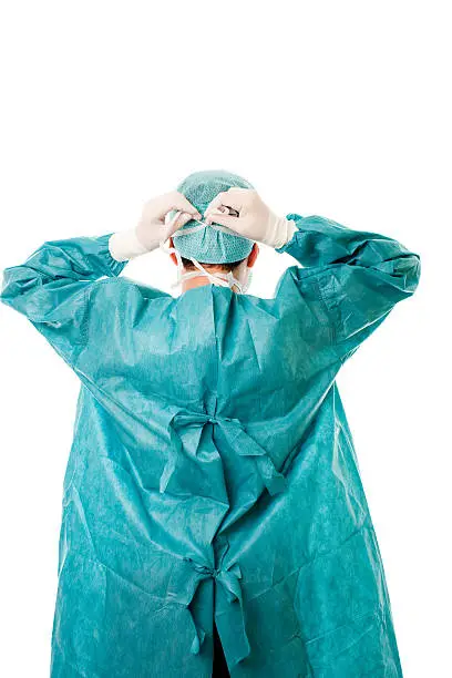 Rear view of a male surgeon tying his mask onto his head.