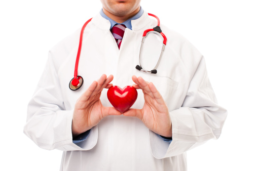 Close up of a doctor holding out a red, heart-shaped sculpture.