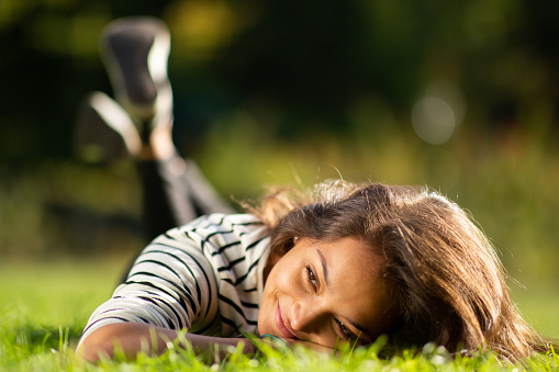 Portrait of smiling young woman lying on grass in park