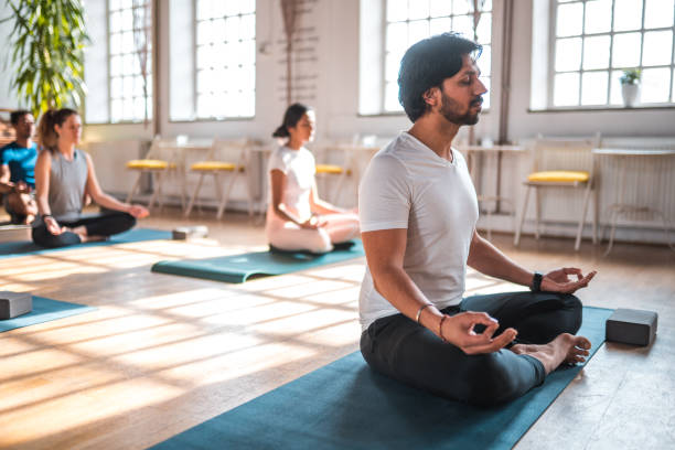 grupo feminino atraente de praticantes de meditação com professor masculino - 15855 - fotografias e filmes do acervo