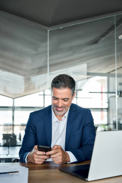 istock Happy mature business man ceo executive sitting in office using phone. 1575140959