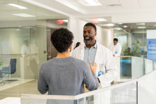 istock Male doctor smiles as unrecognizable man asks questions 1575142468