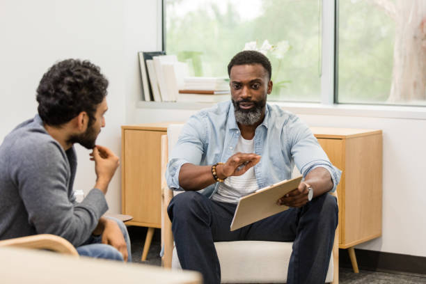 istock Male therapist gestures while giving advice to male client 1575142515