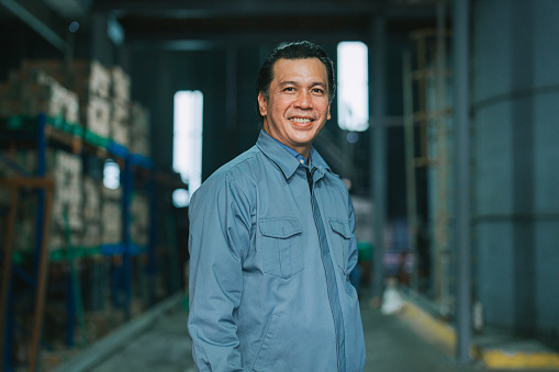 Asian Malay mature man factory manager looking at camera smiling