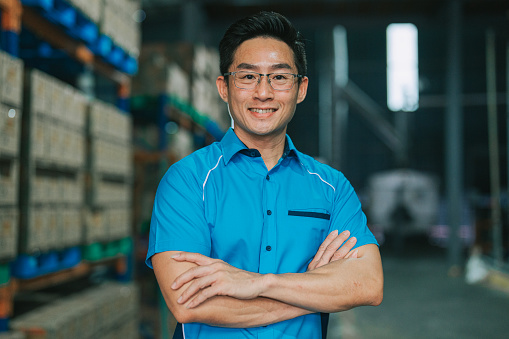Asian Chinese Male Warehouse worker arms crossed looking at camera smiling