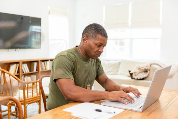 Mature male soldier uses his computer to type an email to his family
