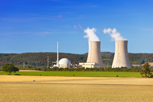 A nuclear power station with hill landscape and blue sky. Two motion blurred cyclists in the foreground.