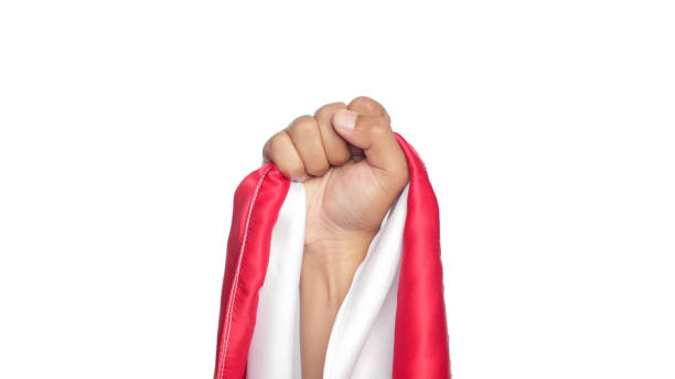 Human hand holding a red and white ribbon as a symbol of the Indonesian flag isolated.