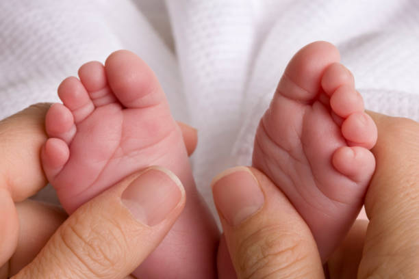 istock Mom Holds Newborn Baby's Tiny Feet 157523547