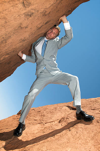 istock Struggling Businessman Carrying Huge Rock Into Sky 157523592