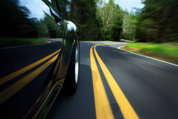 Sports car on country road. Camera mounted shot from the side of a sports car on a nice winding road. View is from the front to the rear with motion blur. driving winding road stock pictures, royalty-free photos & images