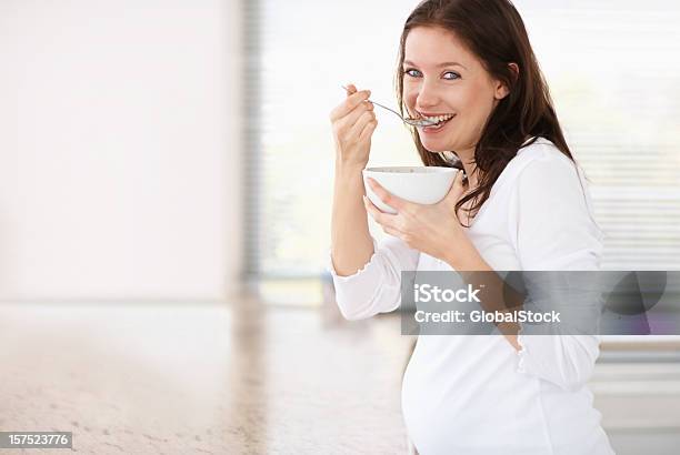 Hermosa Mujer Embarazada Que Tiene Un Tazón De Cereales Foto de stock y más banco de imágenes de Comer