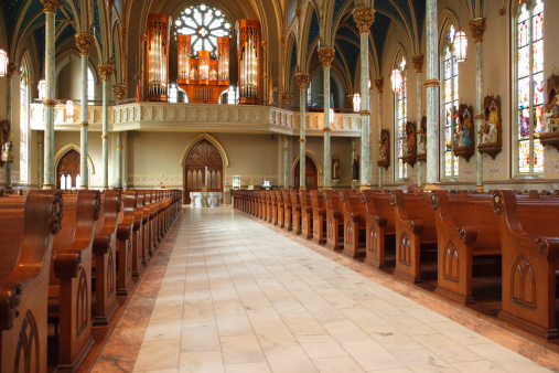Pews, statue of St Francis of Assisi and stations of the cross in a Roman Catholic church