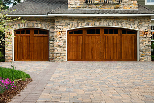 Pavers, custom doors, and stone on upscale home. Pavers, wood custom garage doors, landscaping and beautiful stone exterior walls on a custom home. driveway stock pictures, royalty-free photos & images