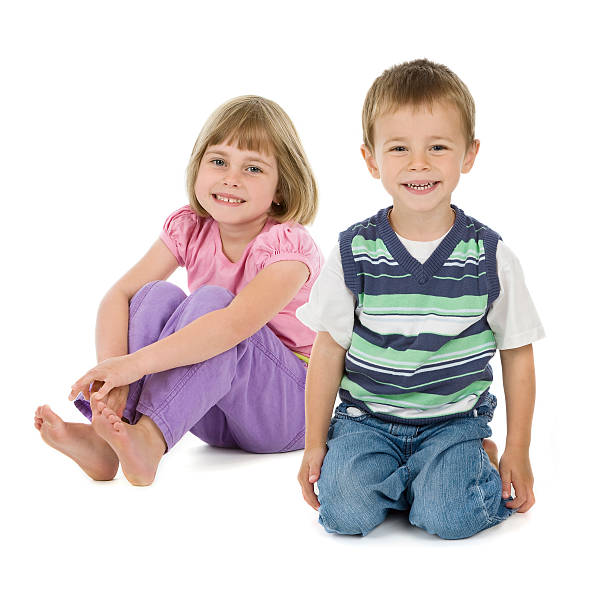 istock Young boy an girl sitting on white background smiling 157524323