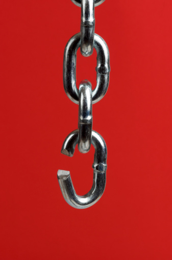 Extreme closeup of taunt stainless steel chain on red background.  One link is open