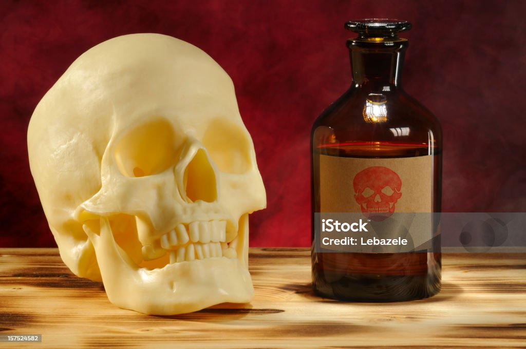 Skull and Bottle (With Label) Skull and old chemical bottle is on wooden desk. A label with skull was added. Abstract Stock Photo