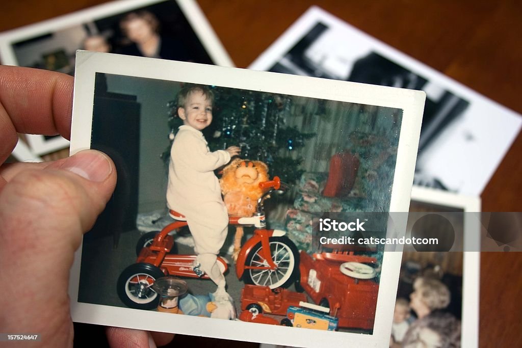 Hand holds Vintage photograph of boy on tricycle at christmas  Christmas Stock Photo