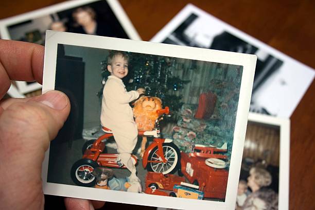 Hand holds Vintage photograph of boy on tricycle at christmas stock photo