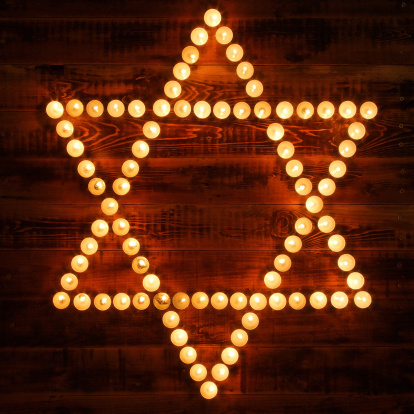 Candles form Star of David on wooden background