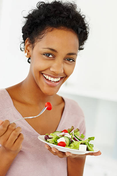 istock Smiling young lady eating green leafy salad 157524777