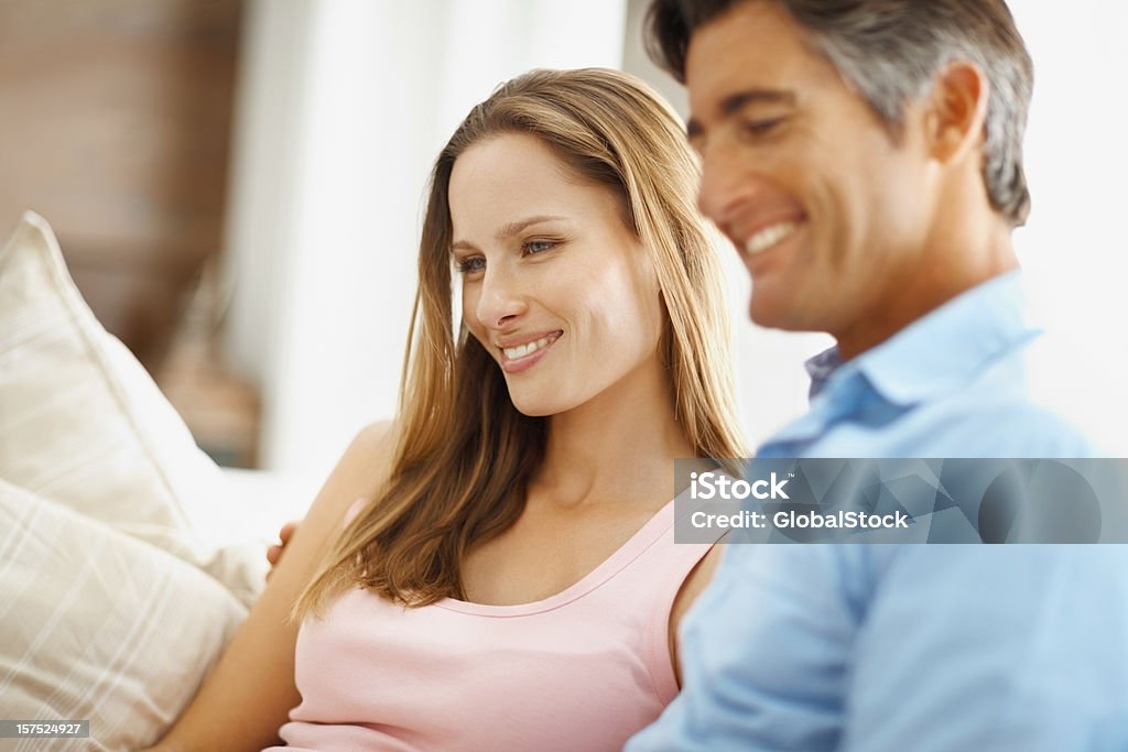 Casal sentado em um sofá e sorrindo - Foto de stock de 30 Anos royalty-free