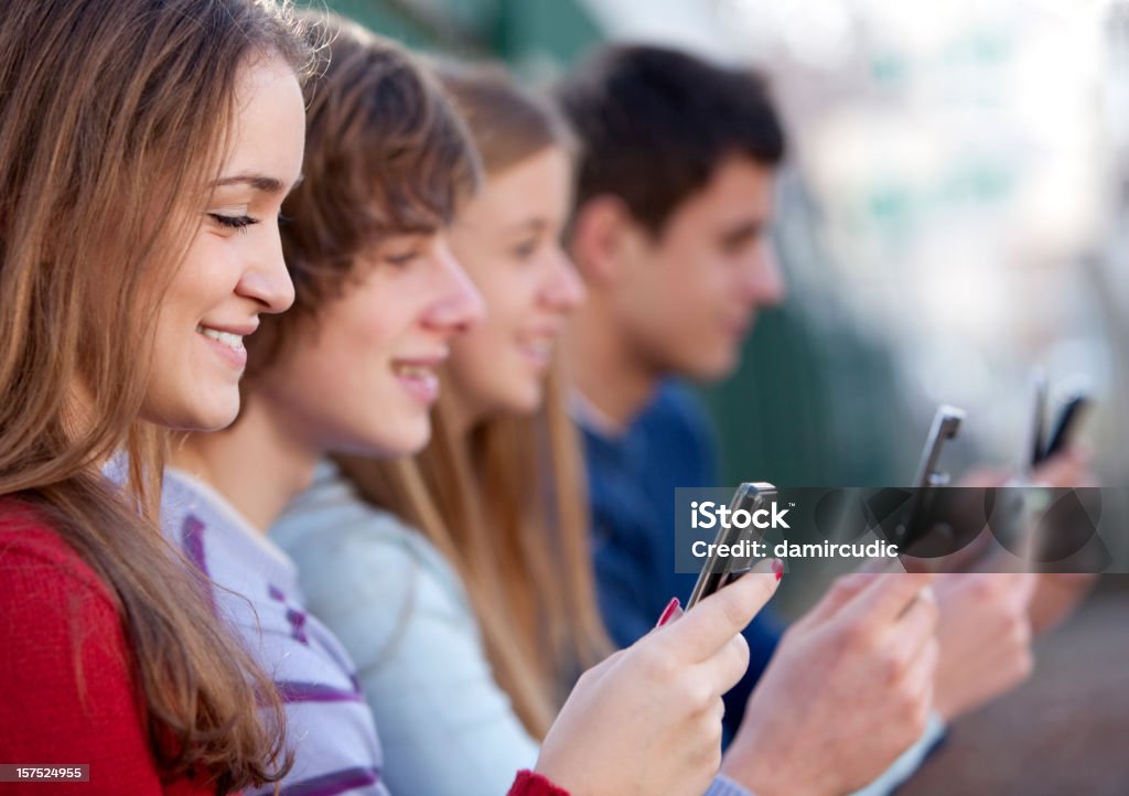 Los jóvenes hombres y mujeres de retención de teléfonos móviles - Foto de stock de Adolescencia libre de derechos