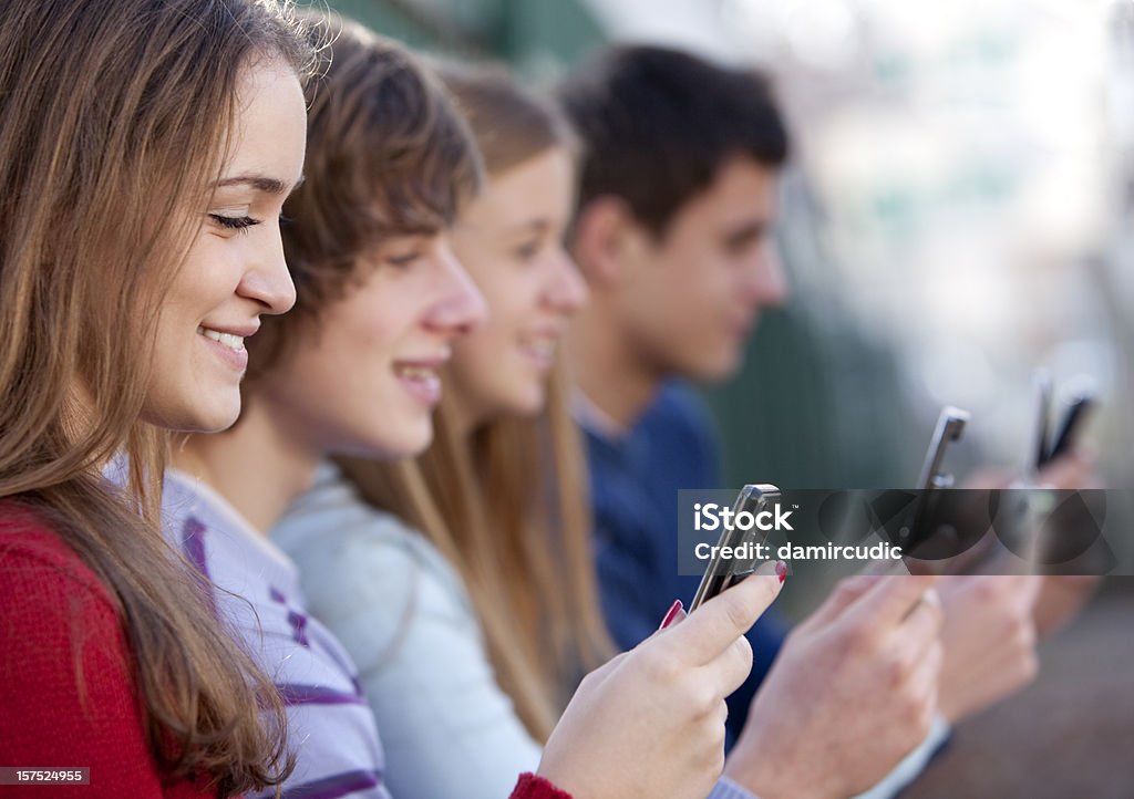 Jovens homens e mulheres segurando os telefones celulares - Foto de stock de Adolescente royalty-free