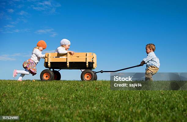 Tre Bambini Piccoli Spingere Tirare E Giocare Con Una Carrozza - Fotografie stock e altre immagini di Lavoro di squadra