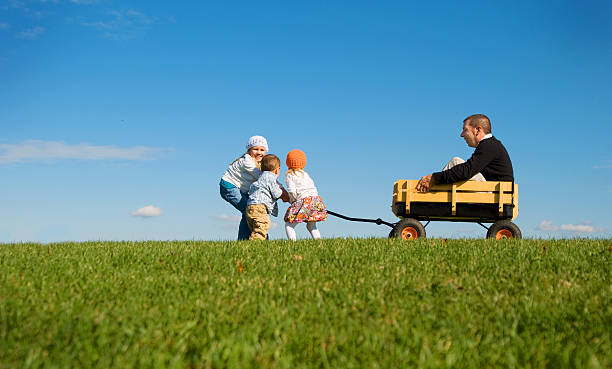 Children pulling Daddy in Wagon stock photo