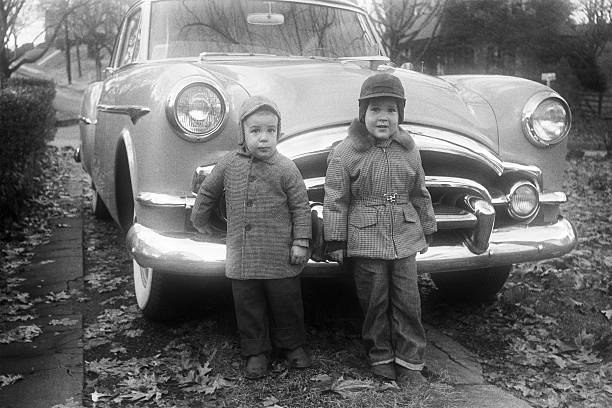 boys and Packard coupe car 1955, retro Two little boys standing in front of a 1953 Packard coupe. Iowa, USA 1955. Scanned film with grain. vintage car family stock pictures, royalty-free photos & images