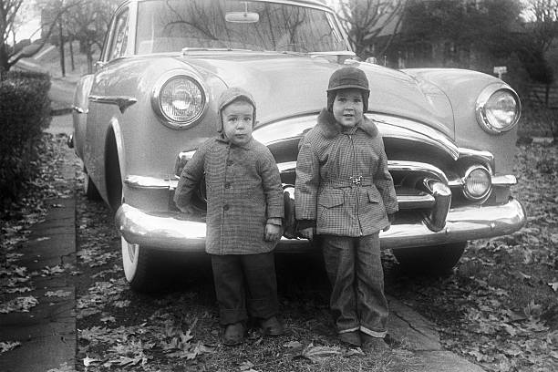 boys and Packard coupe car 1955, retro Two little boys standing in front of a 1953 Packard coupe. Iowa, USA 1955. Scanned film with grain. family pictures stock pictures, royalty-free photos & images