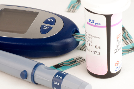 Pulse oximeter with pills, stethoscope and gloves on blue background
