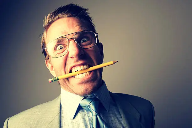Stressed-out veins-popping businessman nears the snapping point chewing on a pencil
