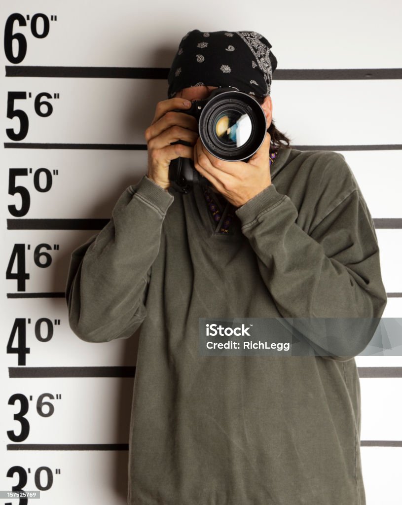 Mugshot of a Photographer A mugshot/booking photo of a man holding a camera. Adult Stock Photo