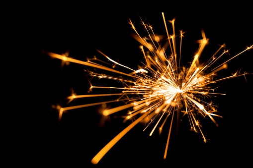 An empty cardboard box on a street corner is illuminated by an array of colorful fireworks, creating an eye-catching display