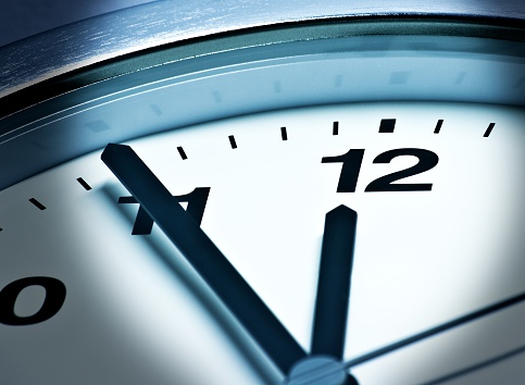 A Modern white wall clock with aluminium frame. Close up to a wall clock, the pointers at quarter pass 4. Selective focus on the number 5 or 5 o'clock. Reflections in the aluminum frame of the watch.