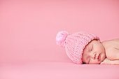 Newborn Baby Girl Sleeping Peacefully on Pink Background
