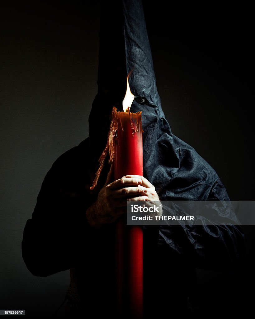 nazareno holding a candle nazareno holding a candle against a dark background during the celebration of semana santa (holy week) in sevilla, spain Candle Stock Photo